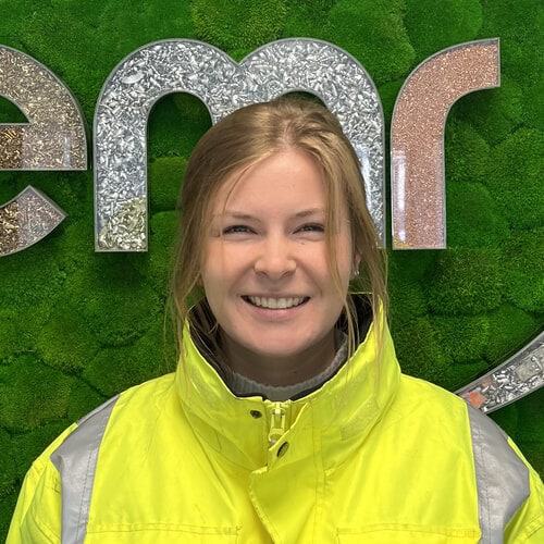 Clara wearing a hi-viz jacket standing in front of an EMR sign